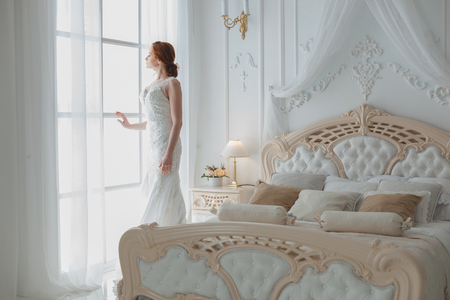 Bride at the window waits for the groom, she is in a wedding dress.の写真素材
