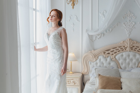 Bride is sad at the window, she is waiting for the groom and is worried.の写真素材