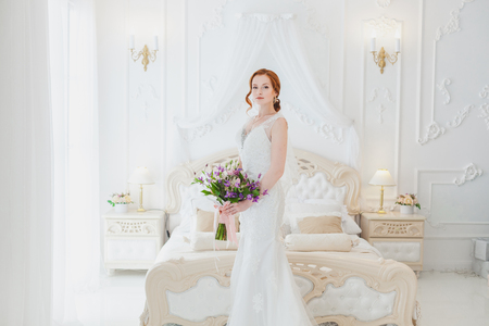 Sweet bride with a wedding bouquet in her hands, she is in the bedroom.の写真素材