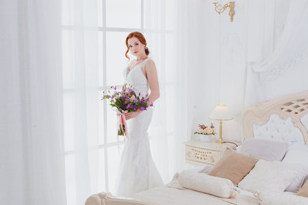 Morning of the bride on her wedding day, she has a wedding bouquet in her hands.の写真素材