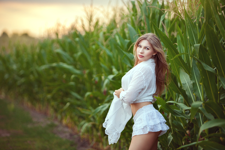 Beautiful woman stands in the field, she turns around and flirts.の写真素材