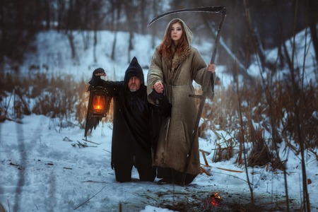 Woman with a scythe and a dreadful dwarf, they are horrifying.の写真素材