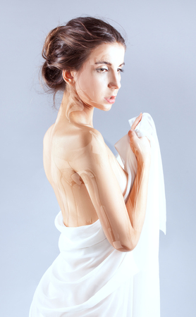 Portrait of a beautiful young woman. She wrapped herself in a white sheetの写真素材