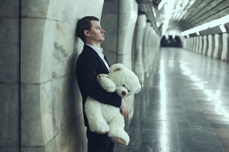 Man is sad with a teddy bear toy in his hands. The concept of his beloved woman did not come to the meeting.の写真素材