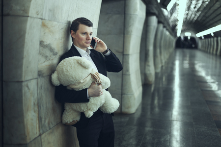 Guy with a plush soft toy calling on the phone congratulating you on the holiday.の写真素材