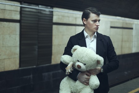 Young man with a teddy bear, he worries before the meeting.の写真素材