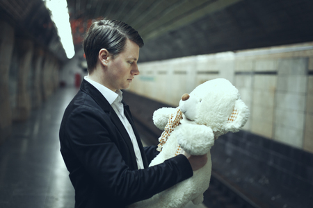 Man is talking with a teddy bear toy. The concept of an eternal adult child.の写真素材