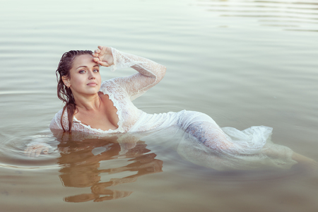 Wet woman lies in the water, she relaxes.の写真素材