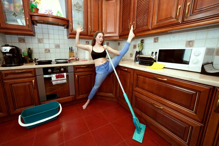 Cheerful apartment cleaner sings and dances with a mop.の写真素材