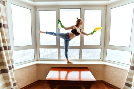 Woman dances while washing the windows in the apartment.の写真素材