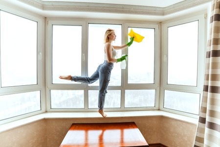 Young woman is engaged in washing windows and at this time she dances.の写真素材