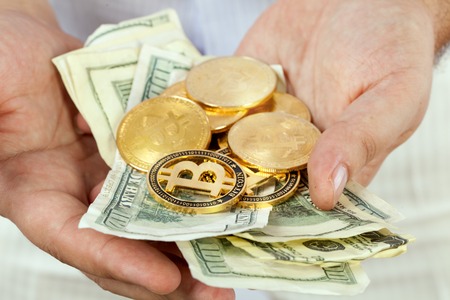 Banknotes and bitcoins in male hands on a white background.の写真素材