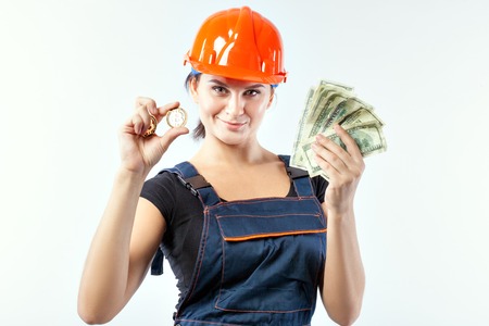 Young woman in helmet with banknotes and bitcoin on white background.の写真素材
