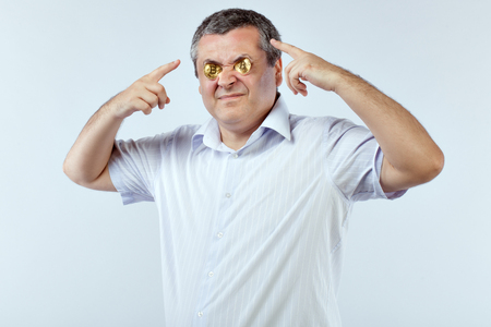 Portrait of a businessman on a white background. He squeezed his eyes bitcoins.の写真素材