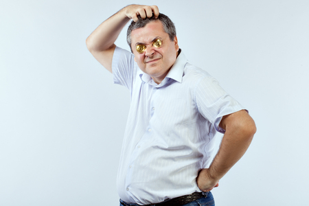 Young businessman with bitcoins in his eyes scratches his head.の写真素材
