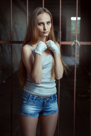 Young woman fighter stands in a fighting stance, she folded her arms together.の写真素材