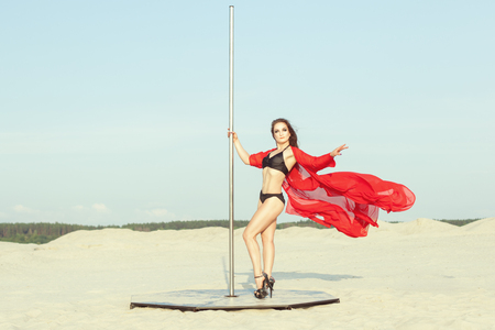 Woman performs a dance around a pole against the background of the desert, she shows the performance.の写真素材