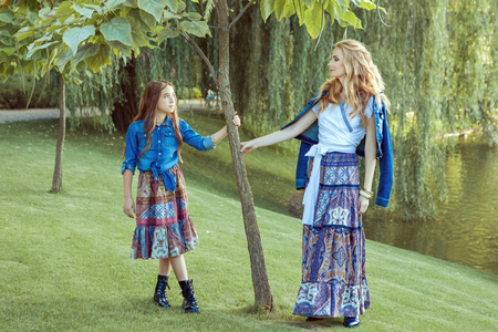 Mom and daughter are standing by the lake. They are dressed in the style of a boho.の写真素材