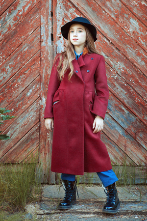 Portrait of a beautiful girl in a red coat and a black hat.の写真素材