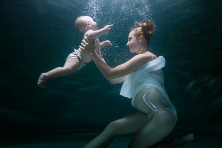 Mom trains an infant to dive under water.の写真素材