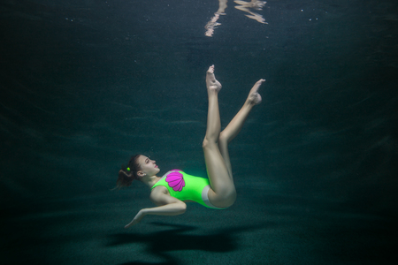 Female gymnast demonstrates pose under the water.の写真素材