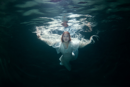 Portrait of a beautiful woman in a white dress under the water.の写真素材