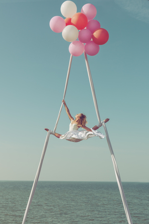Woman is flying in balloons high in the sky, she is demonstrating a sports twine.の写真素材