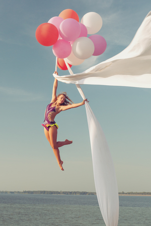 Female acrobat demonstrates stunts during a balloon flight.の写真素材