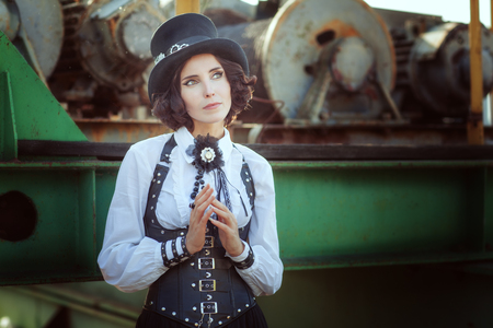 Beautiful young girl dressed in the style of steampunk looks thoughtfully at the sky.の写真素材