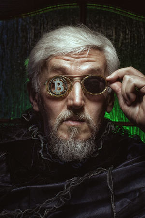 Portrait of an old man with bitcoin in glasses, the personification of a stockbroker.の写真素材