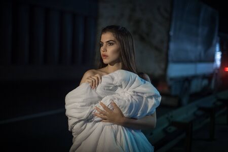 Portrait of a young woman by the road. She wrapped herself in a blanket and warmed up.の写真素材