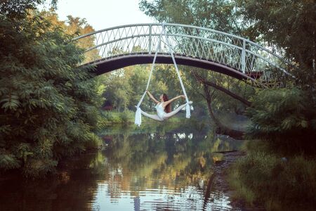 Young acrobat in a white suit does tricks on canvases.の写真素材