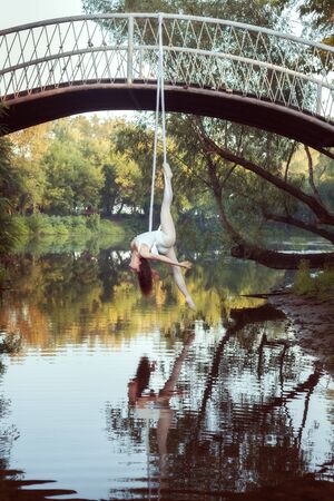 Girl acrobat does sports tricks on canvases over the river..の写真素材