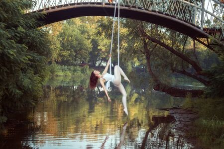 Portrait of acrobat girl on canvases over the river. She does acrobatic stunts.の写真素材