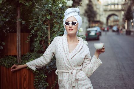 Young woman in a bathrobe with a towel on her head in the street.の写真素材