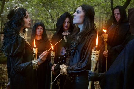 Evil sorceress conducts a magic ritual over a man in the forest.の写真素材