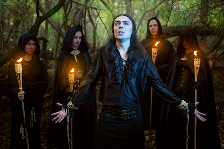 Warlocks in black cloaks spend a magical rite of the man in the woods.の写真素材