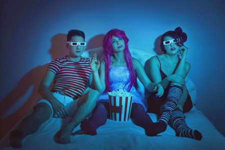 Young people watch home theater with glasses and eat popcorn.の写真素材