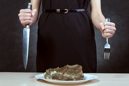 Woman with beautiful hands holds a fork and knife. She is going to cut meat.の写真素材