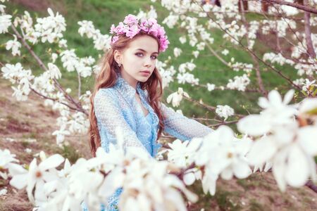 Portrait of an attractive young girl among blooming magnolia trees in the garden.の写真素材
