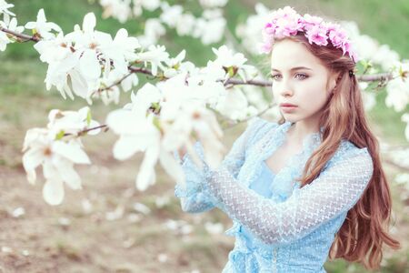 Tender portrait of a young beautiful girl in a garden of blooming magnolias.の写真素材