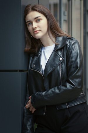 Portrait of a young woman in an autumn black leather jacket. Modern urban style clothing black...