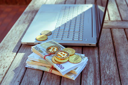There are bitcoins money and a laptop on the table. Bitcoin coins lie on paper euros.の写真素材