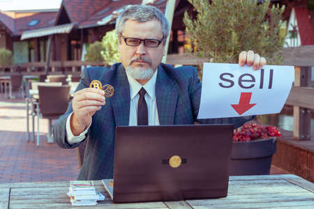 Male businessman trader shows stop with his hand and demonstrates bitcoin.の写真素材