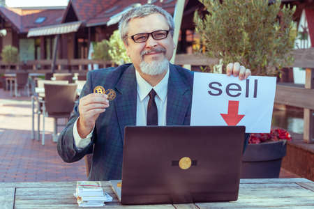 Male businessman trader shows stop with his hand and demonstrates bitcoin.の写真素材