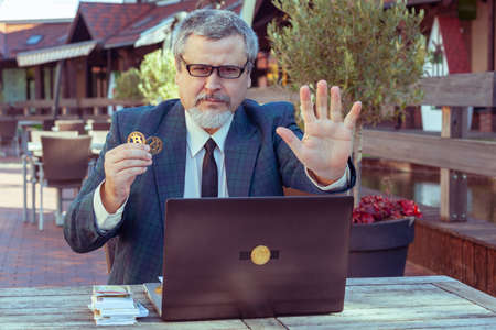 Male businessman trader shows stop with his hand and demonstrates bitcoin.の写真素材