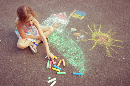 Ukrainian girl child draws children's drawings with chalk on the pavement.の写真素材