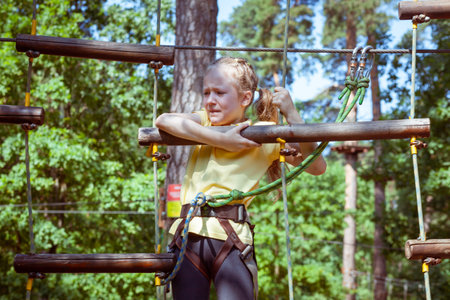 Child in a forest adventure park made of ropes. Children's outdoor climbing entertainment center. Playground for children and sports with a cableway. Sports suspended rope trainer.の写真素材