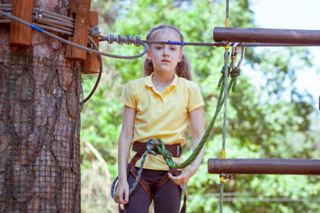 Child in a forest adventure park made of ropes. Children's outdoor climbing entertainment center. Playground for children and sports with a cableway. Sports suspended rope trainer.の写真素材