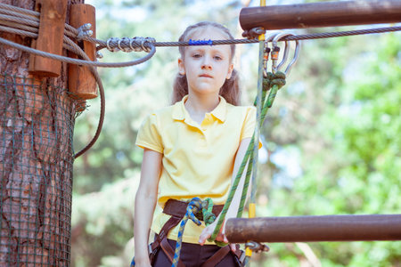 Child in a forest adventure park made of ropes. Children's outdoor climbing entertainment center. Playground for children and sports with a cableway. Sports suspended rope trainer.の写真素材